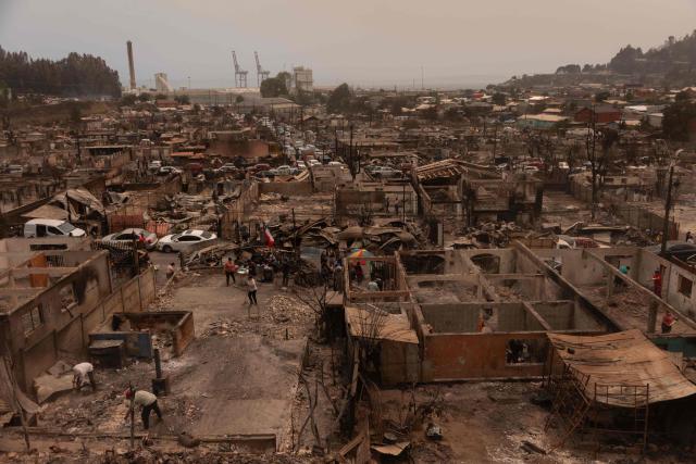 Residents of the Gabriela Mistral neighborhood clear debris from their burnt homes after a wildfire in Lirquen, Chile, on January 19, 2026. Wildfires that have killed 19 people in southern Chile and wiped out entire towns, raged for a third day on January 19, fanned by high temperatures and strong winds at the height of the southern hemisphere summer. (Photo by Raul BRAVO / AFP)
