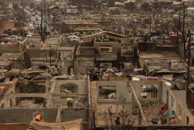 Residents of the Gabriela Mistral neighborhood clear debris from their burnt homes after a wildfire in Lirquen, Chile, on January 19, 2026. Wildfires that have killed 19 people in southern Chile and wiped out entire towns, raged for a third day on January 19, fanned by high temperatures and strong winds at the height of the southern hemisphere summer. (Photo by Raul BRAVO / AFP)
