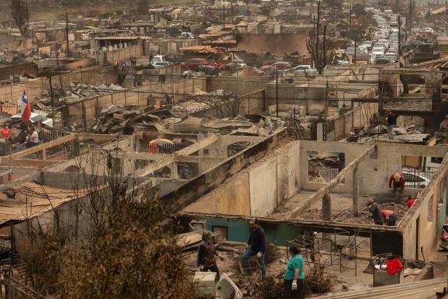 Residents of the Gabriela Mistral neighborhood clear debris from their burnt homes after a wildfire in Lirquen, Chile, on January 19, 2026. Wildfires that have killed 19 people in southern Chile and wiped out entire towns, raged for a third day on January 19, fanned by high temperatures and strong winds at the height of the southern hemisphere summer. (Photo by Raul BRAVO / AFP)