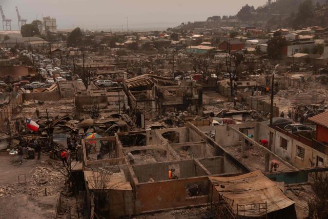 Residents of the Gabriela Mistral neighborhood clear debris from their burnt homes after a wildfire in Lirquen, Chile, on January 19, 2026. Wildfires that have killed 19 people in southern Chile and wiped out entire towns, raged for a third day on January 19, fanned by high temperatures and strong winds at the height of the southern hemisphere summer. (Photo by Raul BRAVO / AFP)