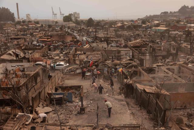 Residents of the Gabriela Mistral neighborhood clear debris from their burnt homes after a wildfire in Lirquen, Chile, on January 19, 2026. Wildfires that have killed 19 people in southern Chile and wiped out entire towns, raged for a third day on January 19, fanned by high temperatures and strong winds at the height of the southern hemisphere summer. (Photo by Raul BRAVO / AFP)