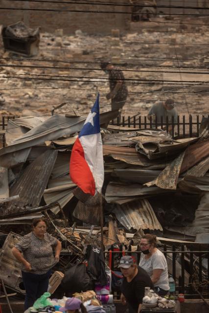 Residents of the Gabriela Mistral neighborhood clear debris from their burnt homes after a wildfire in Lirquen, Chile, on January 19, 2026. Wildfires that have killed 19 people in southern Chile and wiped out entire towns, raged for a third day on January 19, fanned by high temperatures and strong winds at the height of the southern hemisphere summer. (Photo by Raul BRAVO / AFP)