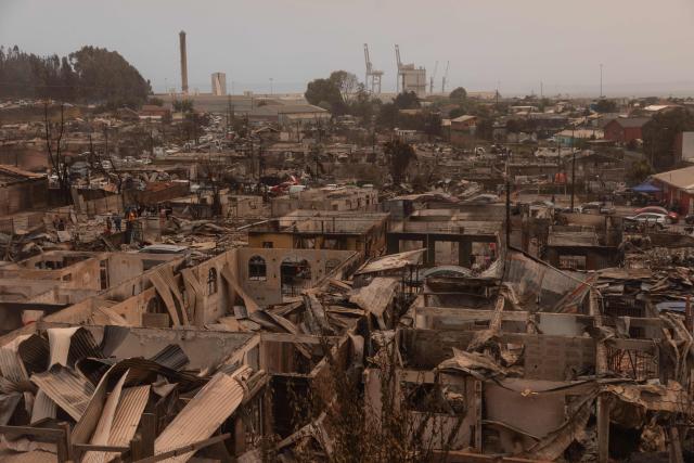 Residents of the Gabriela Mistral neighborhood clear debris from their burnt homes after a wildfire in Lirquen, Chile, on January 19, 2026. Wildfires that have killed 19 people in southern Chile and wiped out entire towns, raged for a third day on January 19, fanned by high temperatures and strong winds at the height of the southern hemisphere summer. (Photo by Raul BRAVO / AFP)
