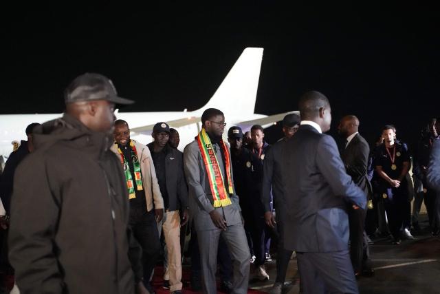 Senegal president Bassirou Diomaye Faye (C) walks with members of Senegal’s national football team upon their arrival in Dakar on January 20, 2025. Senegal’s national football team, crowned African Nations champion thanks to its victory over Morocco on Sunday in Rabat after a high-octane final, landed late Monday night back home, where it was warmly welcomed off the plane by the Senegalese head of state and his government.
The Lions of Teranga, who arrived on a special flight shortly before midnight local time and GMT from Morocco, were congratulated by Senegalese President Bassirou Diomaye Faye, Prime Minister Ousmane Sonko, and members of the government, an AFP journalist observed. (Photo by Carmen Abd Ali / AFP)