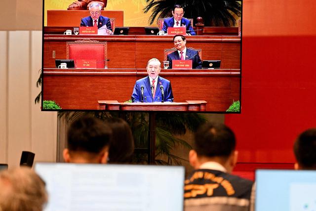 Journalists watch a TV showing General Secretary To Lam reading the political report at the opening ceremony of the 14th National Congress of the Communist Party of Vietnam at the National Convention Centre in Hanoi on January 20, 2026. (Photo by Nhac NGUYEN / AFP)