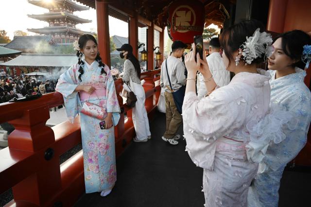 (FILES) Chinese tourists wear kimonos as they visit the Sensoji Temple in the Asakusa district of Tokyo on November 15, 2025. The number of Chinese tourists in Japan plunged 45 percent in December from a year earlier, the transport ministry said on January 20, 2026, as a diplomatic row between Beijing and Tokyo rumbled on. (Photo by GREG BAKER / AFP)