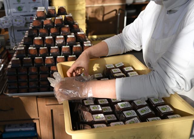 An employee display"Dubai-style" chewy chocolate cookies at a bakery cafe in Seoul on January 20, 2026. Chewy, crunchy and not-too-sweet -- chocolatey round "Dubai-style" cookies have become the must-have dessert in South Korea, with stocks running dry as customers queue as early as 6am for the confectionary. (Photo by Jung Yeon-je / AFP)