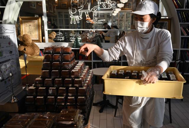 An employee displays "Dubai-style" chewy chocolate cookies at a bakery cafe in Seoul on January 20, 2026. Chewy, crunchy and not-too-sweet -- chocolatey round "Dubai-style" cookies have become the must-have dessert in South Korea, with stocks running dry as customers queue as early as 6am for the confectionary. (Photo by Jung Yeon-je / AFP)