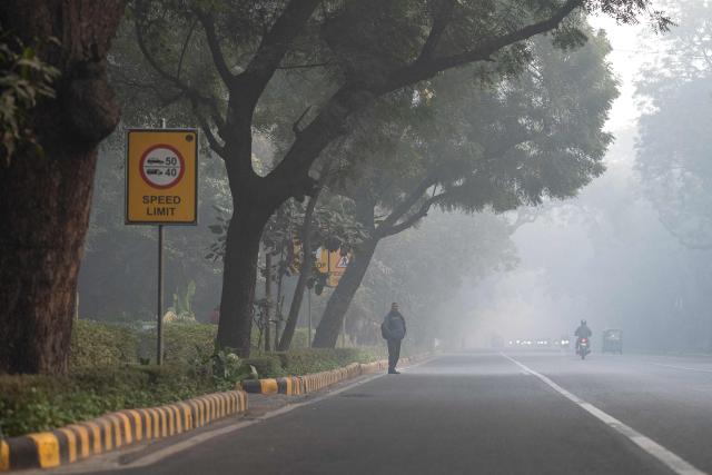 A man waits at a bus stop amid smoggy conditions in New Delhi on January 20, 2026. (Photo by Manan VATSYAYANA / AFP)