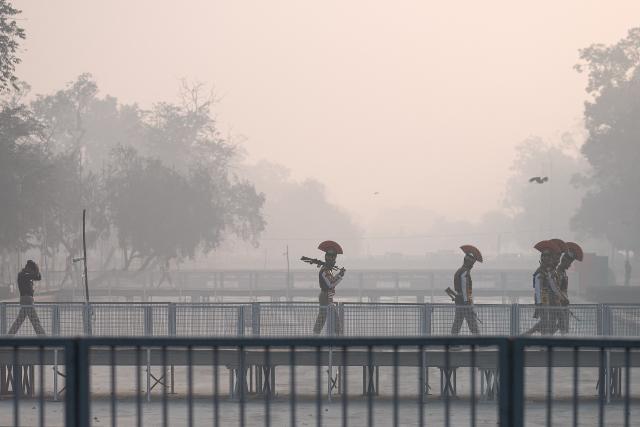 Central Industrial Security Force (CISF) personnel walk across a bridge amid smoggy conditions in New Delhi on January 20, 2026. (Photo by Manan VATSYAYANA / AFP)