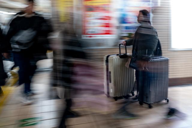 A tourist (R) walks with the suitcase in a subway station of Asakusa district, a popular tourist location in Tokyo on January 20, 2026. A record number of tourists flocked to Japan in 2025, officials said on January 20, despite a steep fall in Chinese visitors in December as a diplomatic row between Beijing and Tokyo rumbled on. (Photo by Philip FONG / AFP)
