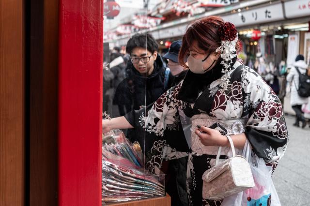 People visit a shopping street in Asakusa district near Sensoji Temple, a popular tourist location in Tokyo on January 20, 2026. A record number of tourists flocked to Japan in 2025, officials said on January 20, despite a steep fall in Chinese visitors in December as a diplomatic row between Beijing and Tokyo rumbled on. (Photo by Philip FONG / AFP)