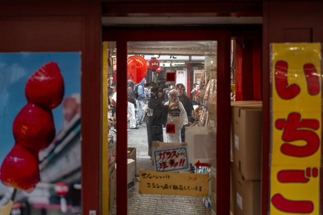 People visit a shopping street in Asakusa district near Sensoji Temple, a popular tourist location in Tokyo on January 20, 2026. A record number of tourists flocked to Japan in 2025, officials said on January 20, despite a steep fall in Chinese visitors in December as a diplomatic row between Beijing and Tokyo rumbled on. (Photo by Philip FONG / AFP)