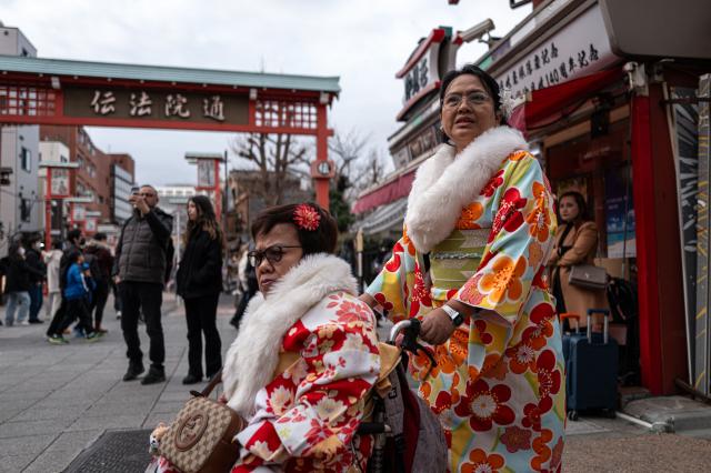 People visit a shopping street in Asakusa district near Sensoji Temple, a popular tourist location in Tokyo on January 20, 2026. A record number of tourists flocked to Japan in 2025, officials said on January 20, despite a steep fall in Chinese visitors in December as a diplomatic row between Beijing and Tokyo rumbled on. (Photo by Philip FONG / AFP)