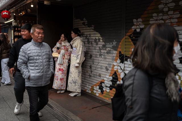 People visit a shopping street in Asakusa district near Sensoji Temple, a popular tourist location in Tokyo on January 20, 2026. A record number of tourists flocked to Japan in 2025, officials said on January 20, despite a steep fall in Chinese visitors in December as a diplomatic row between Beijing and Tokyo rumbled on. (Photo by Philip FONG / AFP)