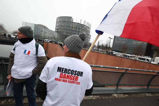 A French farmer, wearing a T-shirt reading "Mercosur: danger in our plates", holds a national flag before European's farmers march towards the European Parliament to protest against the free trade agreement between the European Union and the Mercosur countries, on the eve of a vote on a referral to the courts, in Strasbourg on January 20, 2026. Called by the FNSEA, France's leading national agricultural union, some 4,000 farmers from across the European Union, including Italy, Belgium, and Germany, are expected to attend the protest. MEPs will not vote on the entire agreement with Mercosur until the coming months, but they are set to vote on Wednesday on whether to refer the matter to the Court of Justice of the European Union (CJEU). (Photo by FREDERICK FLORIN / AFP)