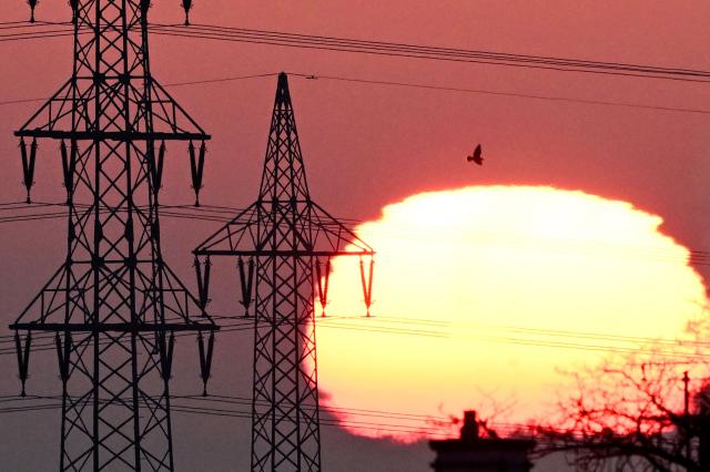 The sun rises behind a pylon and power lines in Frankfurt am Main, western Germany, on January 20, 2026. (Photo by Kirill KUDRYAVTSEV / AFP)