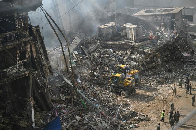 Rescue workers search amid the debris using excavators after a massive fire at a shopping mall in Karachi on January 20, 2026. A fire that ripped through a shopping mall in Pakistan's biggest city has killed at least 21 people, rescuers in Karachi said on January 19. Families rushed to the Gul Plaza building after the blaze erupted late on January 17 at one of the coastal city's busiest malls, where dozens of people were still missing. (Photo by Rizwan TABASSUM / AFP)