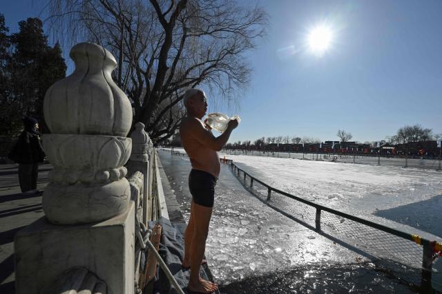 A winter swimming enthusiast rinses his body with fresh water after swimming at the Houhai Lake of the Shichahai scenic area in Beijing on January 20, 2026. Every winter dozens of locals add to their daily routine a frigid lap in the icy waters of Shichahai, a sprawling lake in the center of the Chinese capital. (Photo by Adek BERRY / AFP)