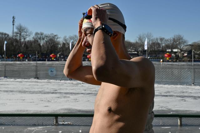 Zhang Xin, a winter swimming enthusiast prepares before swimming at the Houhai Lake of the Shichahai scenic area in Beijing on January 20, 2026. Every winter dozens of locals add to their daily routine a frigid lap in the icy waters of Shichahai, a sprawling lake in the center of the Chinese capital. (Photo by Adek BERRY / AFP)