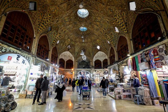 Iranians walk past shops at the Grand Bazaar in the capital Tehran on January 20, 2026. Protests linked to the cost of living broke out in Iran on December 28, spiralling into one of the largest protest movements against the clerical leadership since the Islamic republic was founded in 1979. (Photo by ATTA KENARE / AFP)