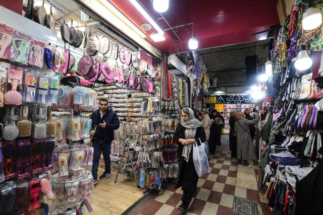 A woman walks past a shop at the Grand Bazaar in the capital Tehran on January 20, 2026. Protests linked to the cost of living broke out in Iran on December 28, spiralling into one of the largest protest movements against the clerical leadership since the Islamic republic was founded in 1979. (Photo by ATTA KENARE / AFP)