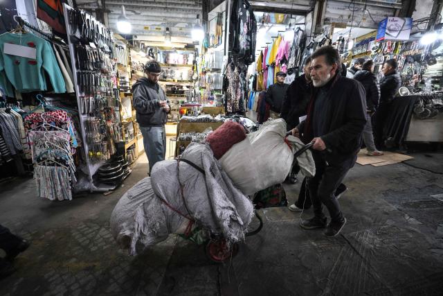 A man wheels bags on a hand truck at the Grand Bazaar in the capital Tehran on January 20, 2026. Protests linked to the cost of living broke out in Iran on December 28, spiralling into one of the largest protest movements against the clerical leadership since the Islamic republic was founded in 1979. (Photo by ATTA KENARE / AFP)