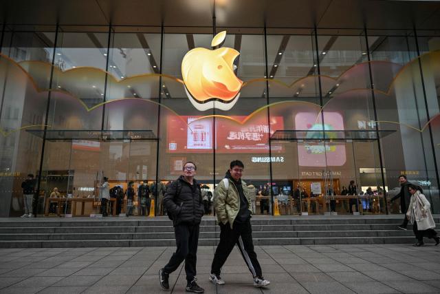 People walk past an Apple store at the Huangpu district in Shanghai on January 20, 2026. (Photo by Hector RETAMAL / AFP)