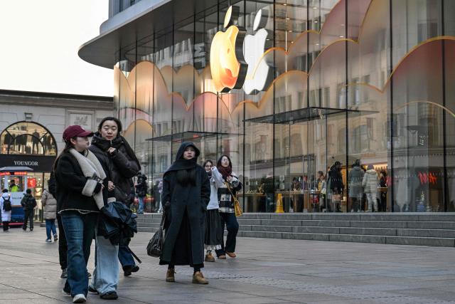 People walk past an Apple store at the Huangpu district in Shanghai on January 20, 2026. (Photo by Hector RETAMAL / AFP)
