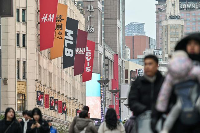 Store logos are seen on a pedestrian street at the Huangpu district in Shanghai on January 20, 2026. (Photo by Hector RETAMAL / AFP)