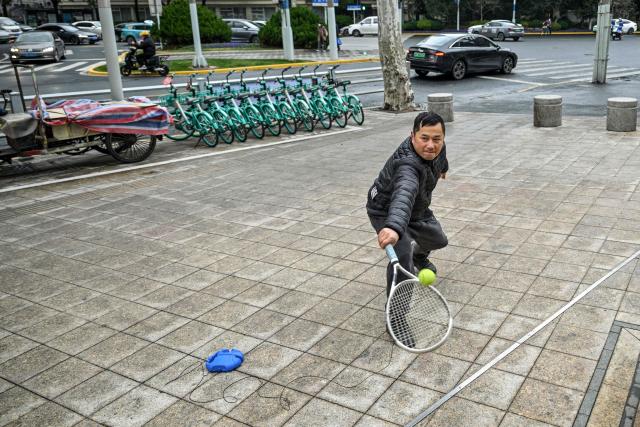 A man plays tennis on a street at the Jing'an district in Shanghai on January 20, 2026. (Photo by Hector RETAMAL / AFP)
