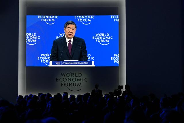 China's Vice-Premier He Lifeng is seen on a big screen as he delivers a speech during the World Economic Forum (WEF) annual meeting in Davos on January 20, 2026. The World Economic Forum takes place in Davos from January 19 to January 23, 2026. (Photo by Fabrice COFFRINI / AFP)