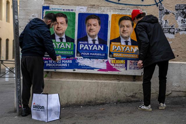 Militants placard electoral posters of Marseille's incumbent Mayor and candidate for re-election in France's upcoming municipal elections Benoit Payan in downtown Marseille on January 20, 2026. French voters head to the polls for municipal elections on March 15 and 22, 2026. (Photo by MIGUEL MEDINA / AFP)