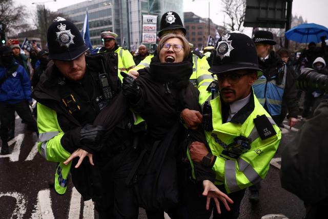 (FILES) Police officers take away a protester who was attempting to block the road during a gathering at the site of the former Royal Mint in London on February 8, 2025, to demonstrate against a proposal to move China's embassy to this site, a stones-throw from the Tower of London. The UK government on January 20, 2026 approved plans for China to build a "mega embassy" in the historic heart of London, eight years after the process began and despite fierce opposition from residents and rights groups. (Photo by HENRY NICHOLLS / AFP)