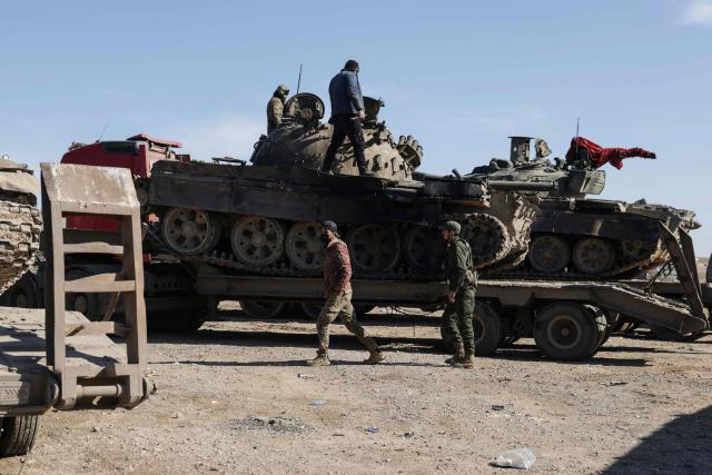 Syrian government forces stand on a tank loaded on a truck along a road in the area of Khirbat At Tamr, south of the city of Hasakeh in northeastern Syria, on January 20, 2026, as they head towards the city. Negotiations have collapsed between the Syrian president and the chief of the country's Kurdish-led forces, a Kurdish official told AFP, as the army deployed reinforcements to flashpoint areas in the north. (Photo by Bakr ALkasem / AFP)