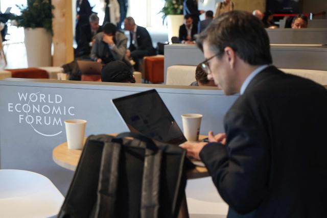 A visitor uses his computer inside the Congress hall during the World Economic Forum (WEF) annual meeting in the Alpine resort of Davos. The World Economic Forum takes place in Davos from January 19 to January 23, 2026. (Photo by Ludovic MARIN / AFP)