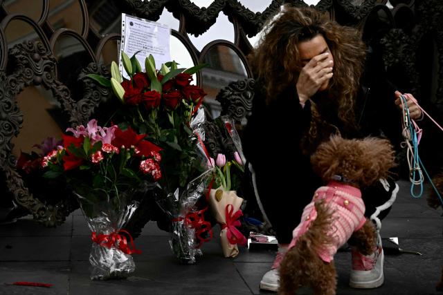 A woman lays flowers by a work of art in front of Valentino's headquarters a day after the death of fashion designer Valentino Garavani at the age of 93, in Rome on January 20, 2026. (Photo by Filippo MONTEFORTE / AFP)
