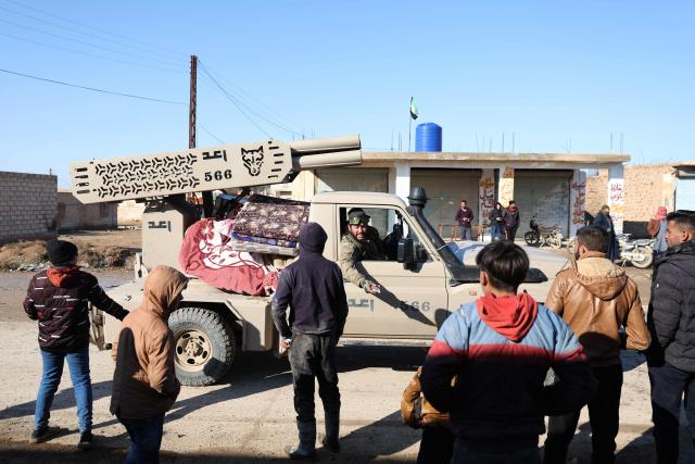 Residents line the sideways of a street, as Syrian government forces enter the city of Ash Shaddadah, south of the city of Hasakeh, in northeastern Syria on January 20, 2026. Negotiations have collapsed between the Syrian president and the chief of the country's Kurdish-led forces, a Kurdish official told AFP, as the army deployed reinforcements to flashpoint areas in the north. (Photo by OMAR HAJ KADOUR / AFP)