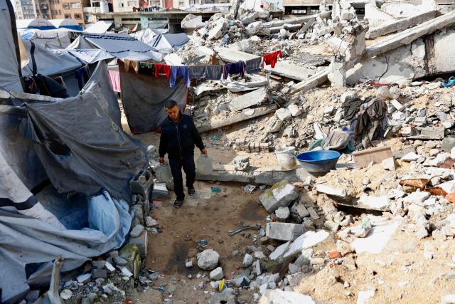 A man carries jerrycans past tents erected next to rubble in Gaza City on January 20, 2026. Day-to-day living conditions for the vast majority of Gaza residents remain extremely precarious, with more than 80 percent of infrastructure destroyed, according to the United Nations. Several humanitarian and UN workers told AFP that while the situation has improved in some areas since the ceasefire, the humanitarian response remains insufficient due to access restrictions imposed by Israeli authorities -- who deny these claims. Water and electricity networks, as well as waste management, no longer function. (Photo by Omar AL-QATTAA / AFP)