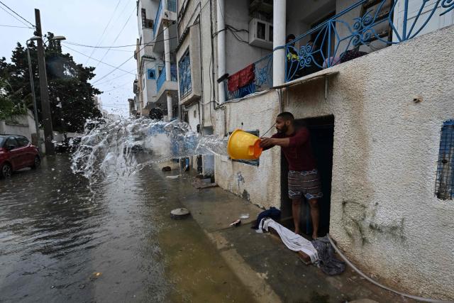 A man uses a bucket to remove flood water from his home, in La Goulette near the capital Tunis, on Januray 20, 2026. Flooding across Tunisia has killed three people, authorities said January 20, with one official reporting a "critical" situation as parts of the North African country experienced their heaviest rainfall in more than 70 years. (Photo by FETHI BELAID / AFP)