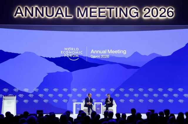 France's President Emmanuel Macron (R) gestures as he speaks next to BlackRock chairman and WEF co-chairman Larry Fink during the World Economic Forum (WEF) annual meeting in Davos on January 20, 2026. The World Economic Forum takes place in Davos from January 19 to January 23, 2026. (Photo by Ludovic MARIN / AFP)