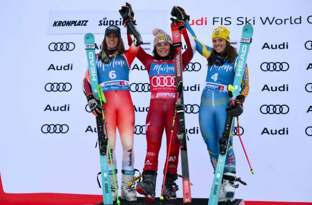 Austria's Julia Scheib (C), winner, Switzerland's Camille Rast, second and Sweden's Sara Hector celebrate on the podium of the Women's Giant Slalom event of FIS Alpine Skiing World Cup in Kronplatz, Plan de Corones, Italy, on January 20, 2026. (Photo by Marco BERTORELLO / AFP)