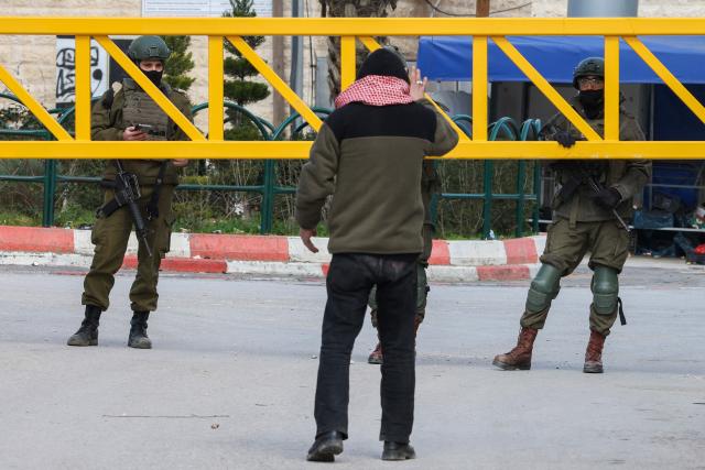 A Palestinian man argues with soldiers as he tries to reach his home, after the Israeli army closed part of the H2 southern sector of the occupied West Bank city of Hebron, and announced a curfew as they search for weapons and Palestinians on their wanted list, on January 20, 2026. Following the 1995 Oslo Agreement and subsequent 1997 Hebron Agreement, Palestinian cities in the West Bank were placed under the exclusive jurisdiction of the Palestinian Authority, with the exception of Hebron, which was split into two sectors: H1 is controlled by the Palestinian Authority and H2 – which includes the Old City of Hebron – remaining under the military control of Israel. Most Palestinians live in the H2 sector. (Photo by HAZEM BADER / AFP)