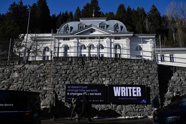 This photograph taken on January 20, 2026 shows pedestrians walking past AI promotional posters at the foot of the Belvedere hotel during the World Economic Forum (WEF) annual meeting in Davos. The World Economic Forum takes place in Davos from January 19 to January 23, 2026. (Photo by INA FASSBENDER / AFP)