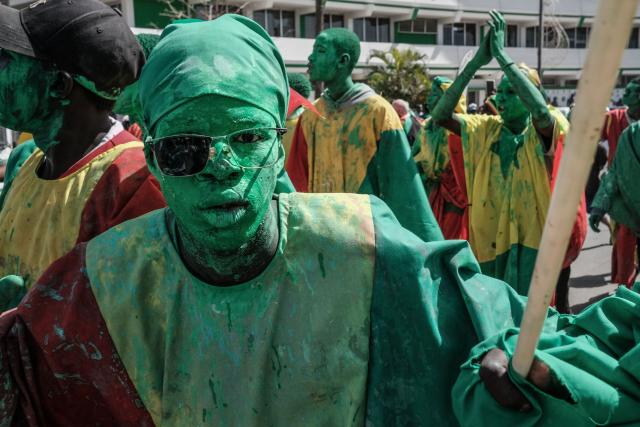 Senegalese football supporters, painted in green, gesture as they gather with other supporters waiting for the bus with the team on board to drive past during a trophy parade in the streets of Dakar on January 20, 2026 as they celebrate Senegal winning the Africa Cup of Nations (CAN) that was hosted in Morocco. Senegal won the Africa Cup of Nations in Rabat on January 18, 2026, Pape Gueye's extra-time winner sinking hosts Morocco 1-0 after a chaotic final that saw the eventual champions storm off the pitch late in the game. (Photo by GUY PETERSON / AFP)