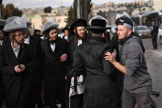 A member of Israel's security forces disperses ultra-Orthodox Jews during a protest against a court ruling to allow autopsies to be carried out on two babies that died in an unlicensed daycare centre a day earlier in Jerusalem, on January 20, 2026. Israeli doctors declared two babies dead after medics evacuated 55 children from a daycare centre in Jerusalem on January 19, with local media reporting the incident may have been linked to the facility's heating system. (Photo by ilia yefimovich / AFP)