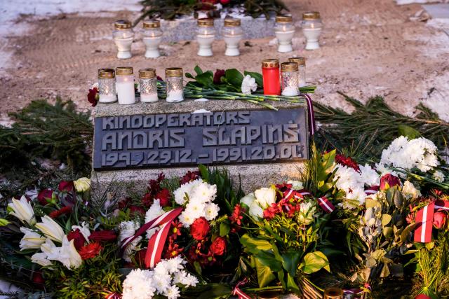 The grave bearing the name of a victim who fell during the January 1991 events is pictured at the burial site of the 2nd Forest Cemetery in Riga, Latvia on January 20, 2026 during a remembrance ceremony for those who died during the 1991 "Barricades" on January 20, 1991. Latvia marks the 35th anniversary of the events known as the 1991 "Barricades", when supporters of Latvian independence non-violently defended the country's freedom against military attacks and opponents of independence. (Photo by Gints Ivuskans / AFP)