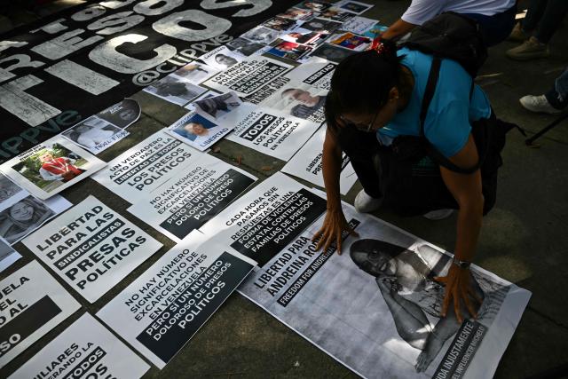 Relatives of political prisoners protest displaying pictures and signs in front of the public prosecutor's office in Caracas on January 20, 2026. Dozens of journalists, government critics and activists have been freed in Venezuela since the US military deposed Nicolas Maduro this month. Rights group Foro Penal counts 90 political prisoner releases since January 8, while interim president Delcy Rodriguez says 406 people have been freed since December. Several prominent opposition figures, however, remain jailed despite US pressure (Photo by RONALDO SCHEMIDT / AFP)