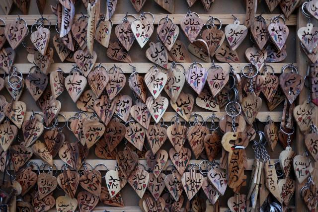 Wooden key rings with names carved on them, are displayed after being crafted in the shop in Ramallah, in the occupied West Bank, on January 20, 2026. (Photo by Zain JAAFAR / AFP)