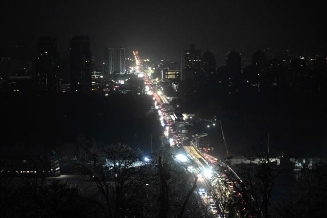Cars drive along a road during a power outage in Kyiv on January 20, 2026, amid the Russian invasion of Ukraine. An overnight Russian bombardment left thousands of residential buildings in Kyiv without heating and water in -14C temperatures on January 20, 2026, when the Ukrainian capital was already scrambling to restore vital utilities destroyed in earlier attacks. (Photo by Sergei GAPON / AFP)